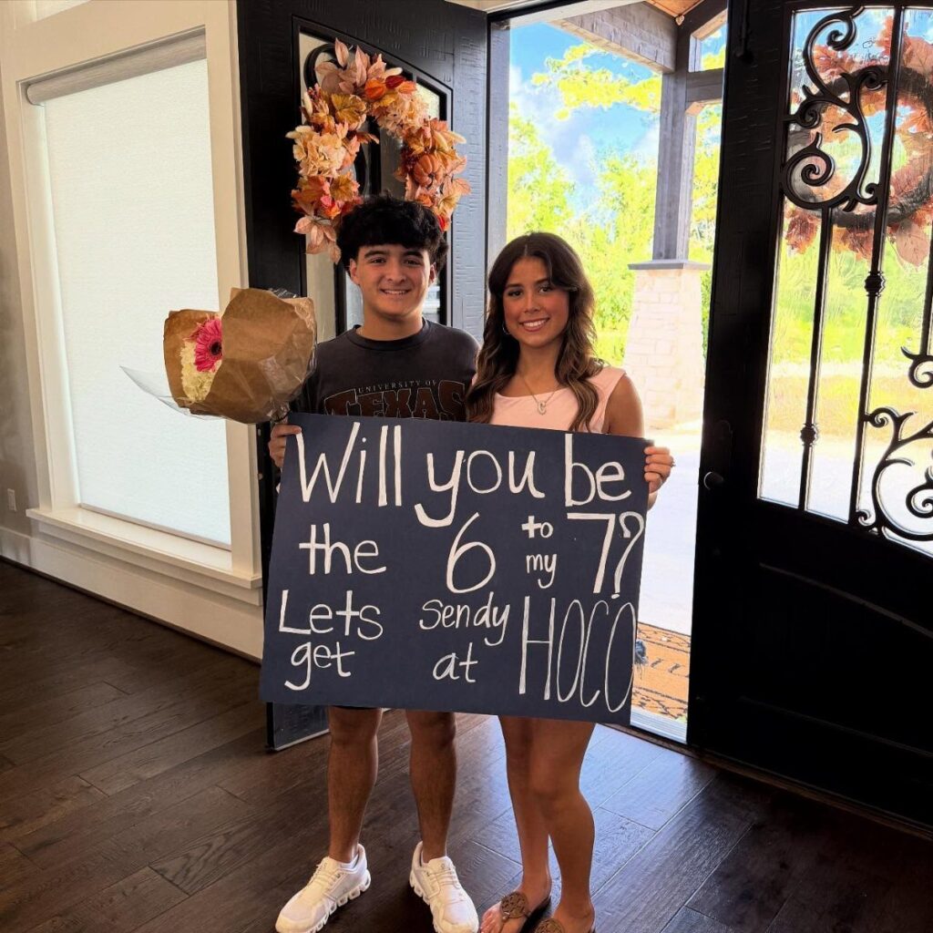 Teenage couple holding a homecoming proposal sign that says 6 to my 7.