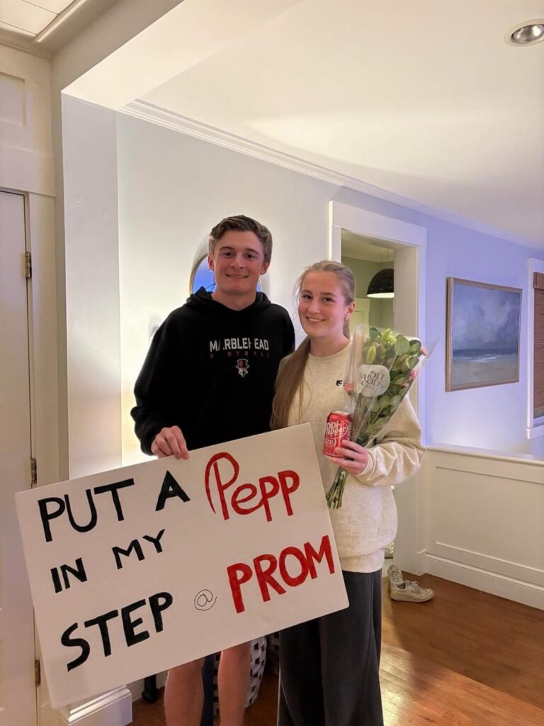 Teenage couple posing with a Dr Pepper themed prom proposal sign and soda can.