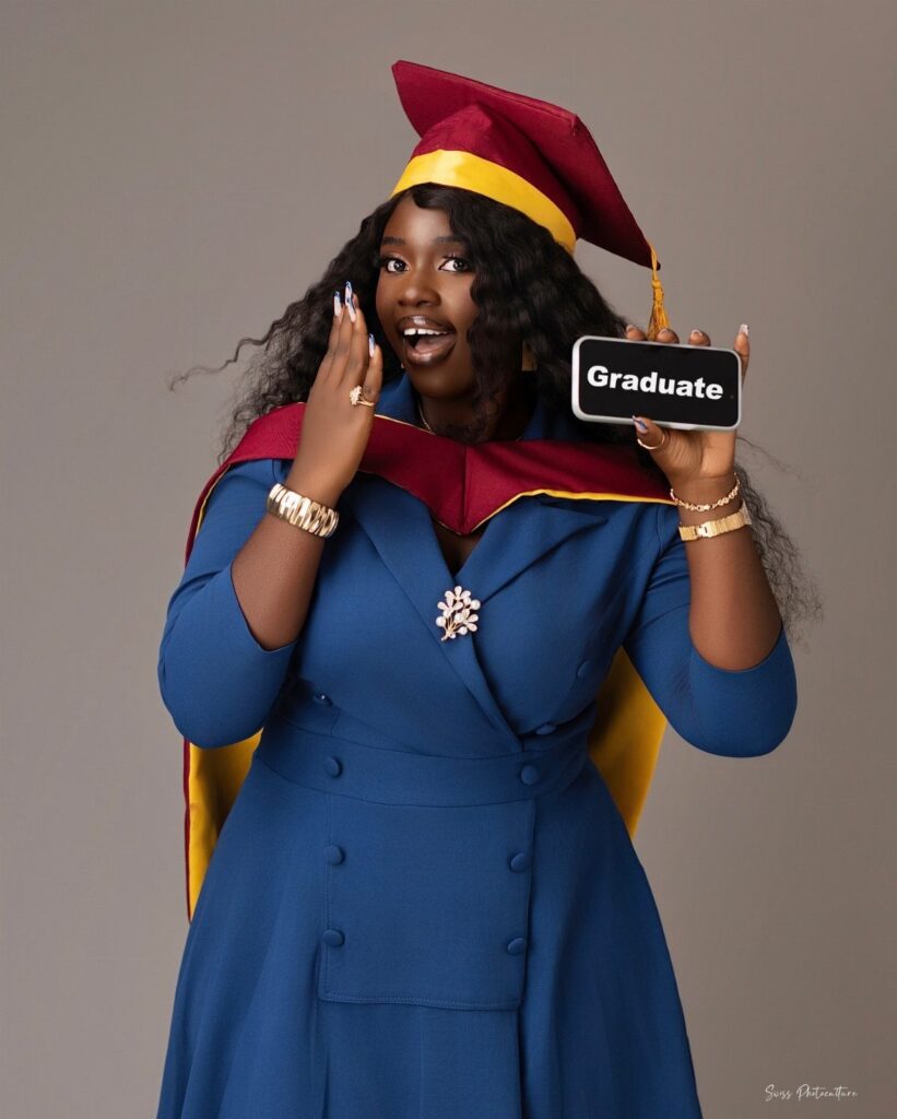 Woman in blue dress and graduation regalia holding a Graduate sign in studio