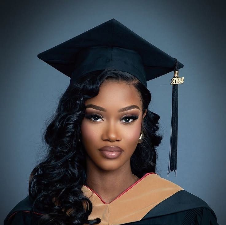 Woman with long curly black hair wearing a black graduation cap and gown.