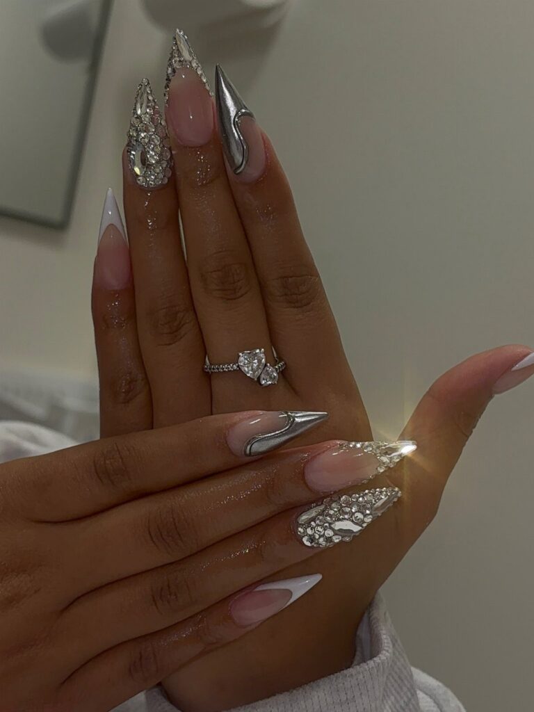 Long pointed acrylic nails with silver chrome, French tips, and sparkling rhinestones.